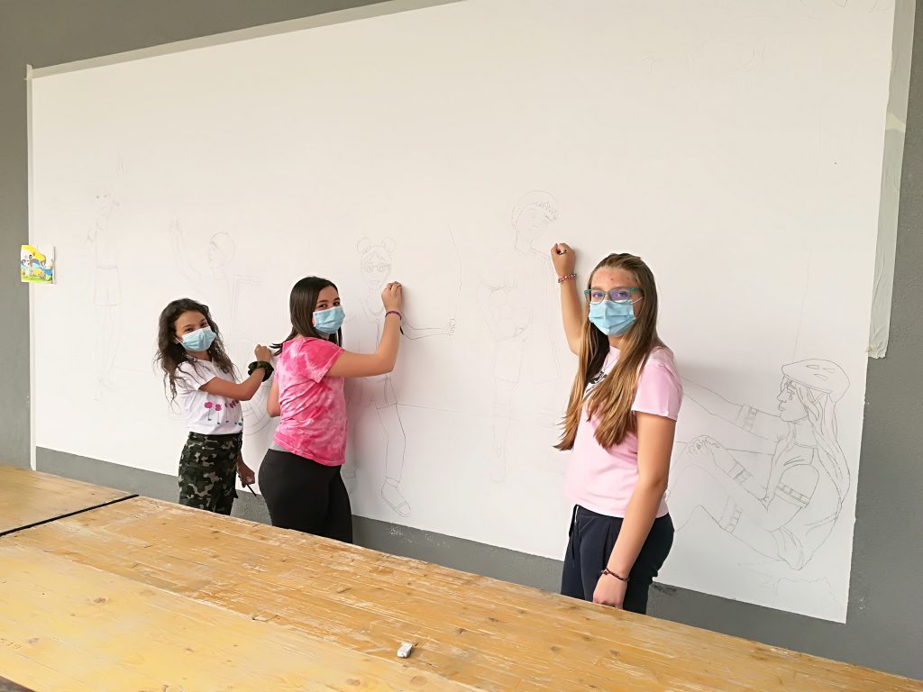 Tre ragazze disegnano su un muro bianco